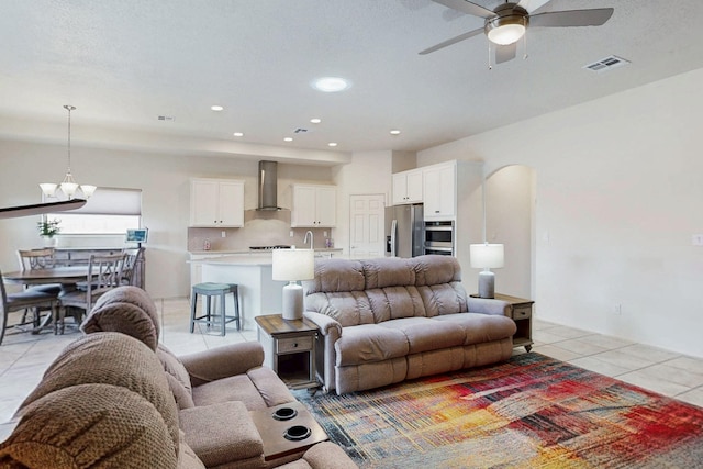 living room with recessed lighting, visible vents, light tile patterned floors, arched walkways, and ceiling fan with notable chandelier