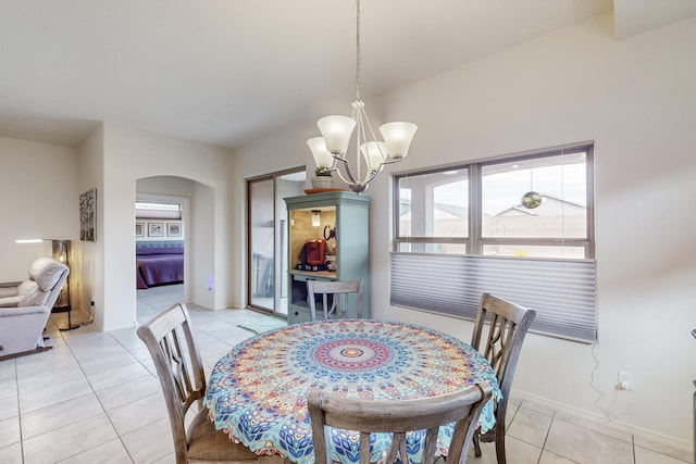 dining room with a notable chandelier, light tile patterned floors, baseboards, and arched walkways