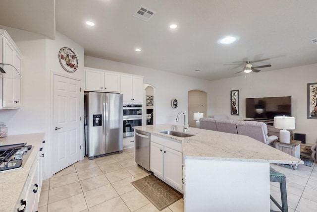 kitchen with a sink, ceiling fan, arched walkways, appliances with stainless steel finishes, and visible vents