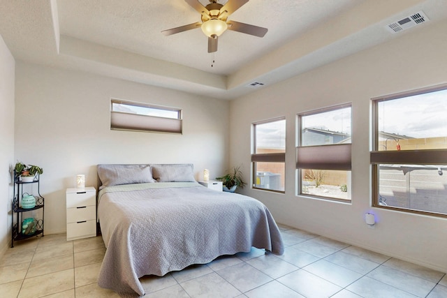 bedroom featuring light tile patterned flooring, a raised ceiling, visible vents, and a ceiling fan