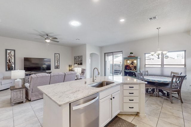 kitchen featuring light stone counters, visible vents, arched walkways, a sink, and stainless steel dishwasher