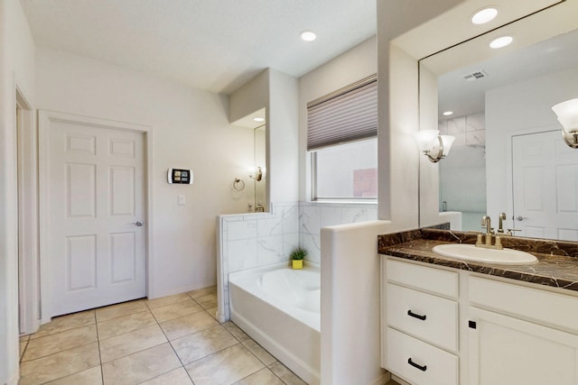 full bath featuring tile patterned floors, a bath, vanity, baseboards, and visible vents