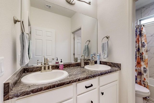 full bathroom with double vanity, toilet, visible vents, and a sink