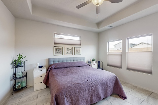 bedroom featuring a tray ceiling, light tile patterned floors, baseboards, and visible vents