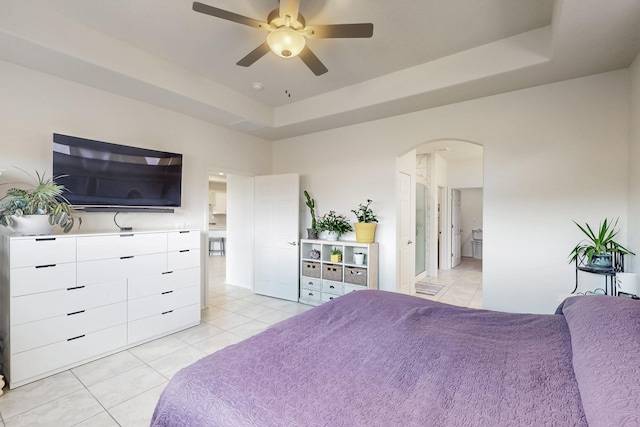 bedroom with light tile patterned floors, arched walkways, a raised ceiling, and ceiling fan