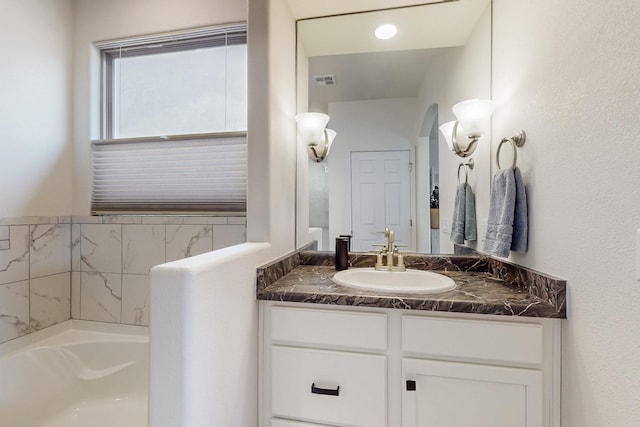 bathroom with visible vents, a washtub, and vanity