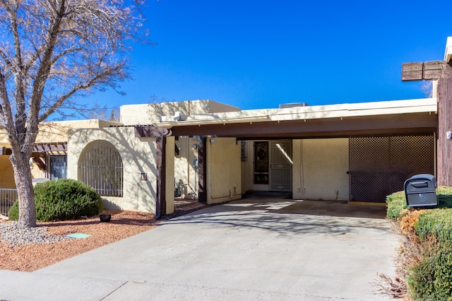 view of front of property with concrete driveway, an attached carport, and stucco siding