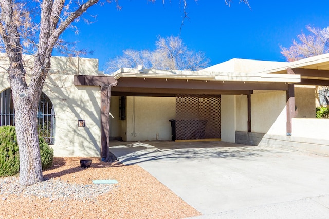 exterior space with a carport, concrete driveway, and stucco siding