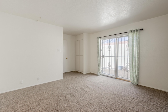 unfurnished room with light colored carpet, a textured ceiling, and baseboards