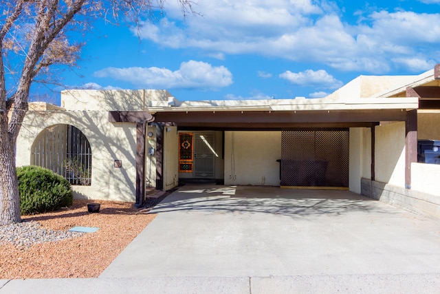 southwest-style home featuring an attached carport, driveway, fence, and stucco siding