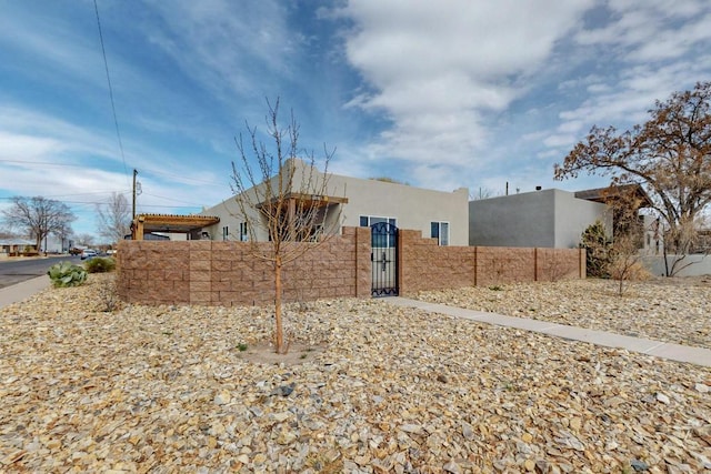 pueblo-style house featuring a fenced front yard, a gate, and stucco siding