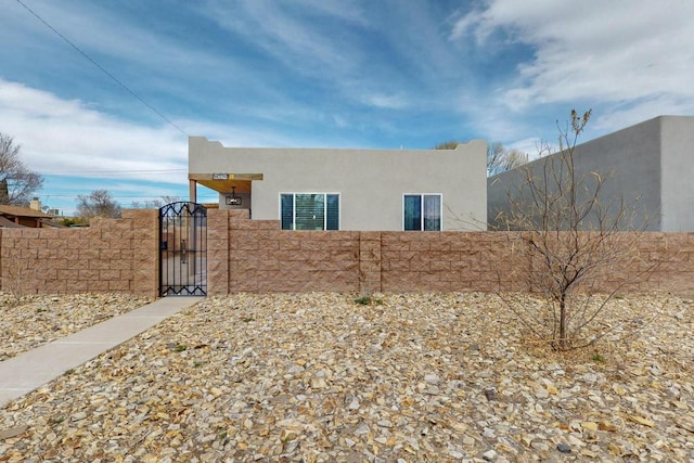 view of property exterior with a fenced front yard, a gate, and stucco siding