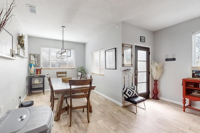 dining space with light wood-style floors, a healthy amount of sunlight, visible vents, and baseboards