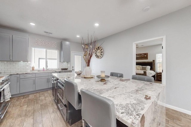 kitchen featuring light stone counters, a breakfast bar, tasteful backsplash, appliances with stainless steel finishes, and a kitchen island