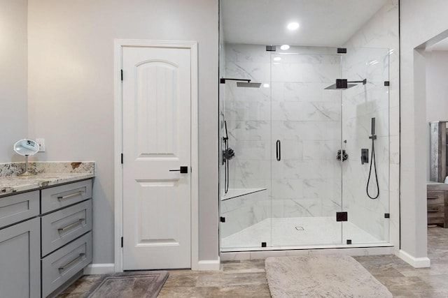 full bath featuring a stall shower, vanity, and baseboards