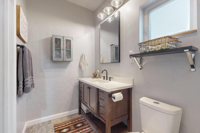 bathroom featuring toilet, baseboards, wood finished floors, and vanity