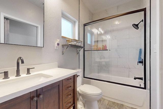 bathroom featuring toilet, combined bath / shower with glass door, wood finished floors, and vanity