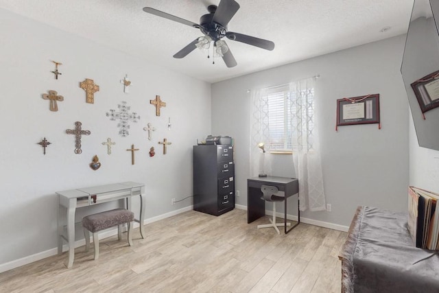 interior space with baseboards, ceiling fan, a textured ceiling, and light wood-style floors