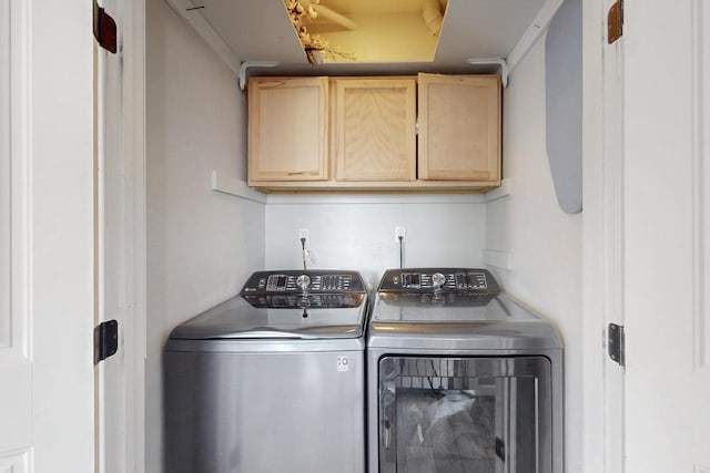 clothes washing area with independent washer and dryer and cabinet space