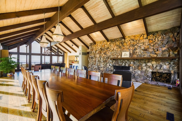 dining room with a fireplace, a notable chandelier, visible vents, beamed ceiling, and hardwood / wood-style flooring