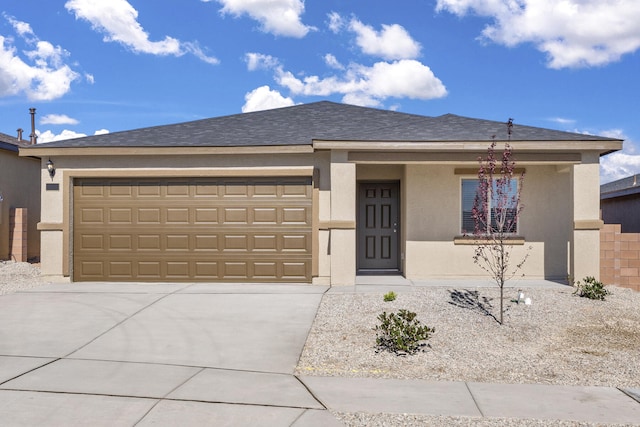 view of front of home featuring concrete driveway, a shingled roof, an attached garage, and stucco siding