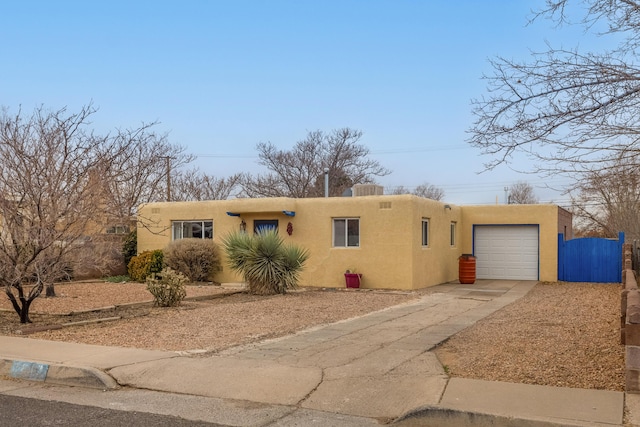 pueblo-style house with a garage, driveway, and stucco siding