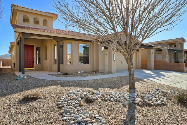 view of front facade with a tile roof, driveway, an attached garage, and stucco siding