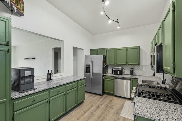 kitchen featuring stainless steel appliances, light wood-type flooring, green cabinetry, and decorative backsplash