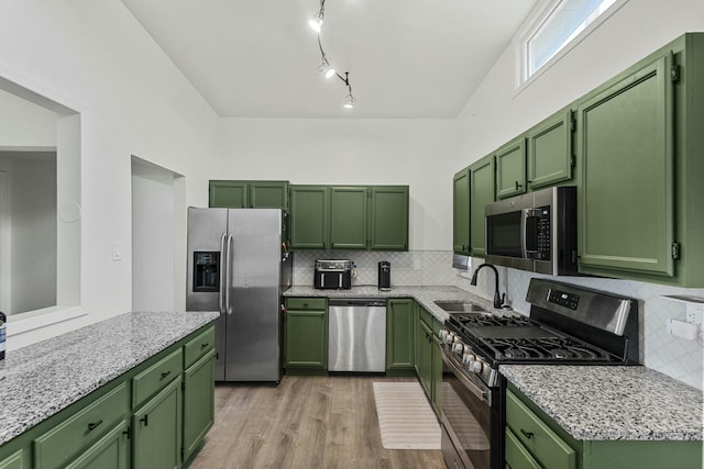 kitchen with green cabinets, appliances with stainless steel finishes, a sink, and light wood-style floors