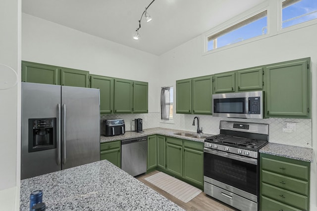 kitchen featuring stainless steel appliances, tasteful backsplash, a sink, and green cabinetry