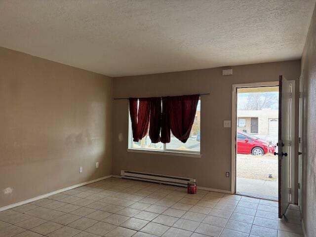 empty room with baseboards, light tile patterned flooring, a textured ceiling, and baseboard heating