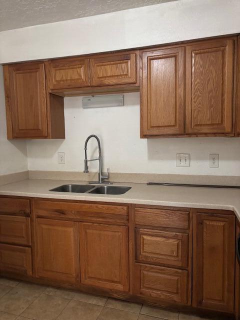 kitchen featuring light countertops, brown cabinetry, and a sink