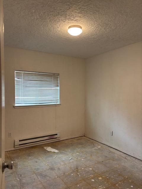 unfurnished room with a textured ceiling and baseboard heating