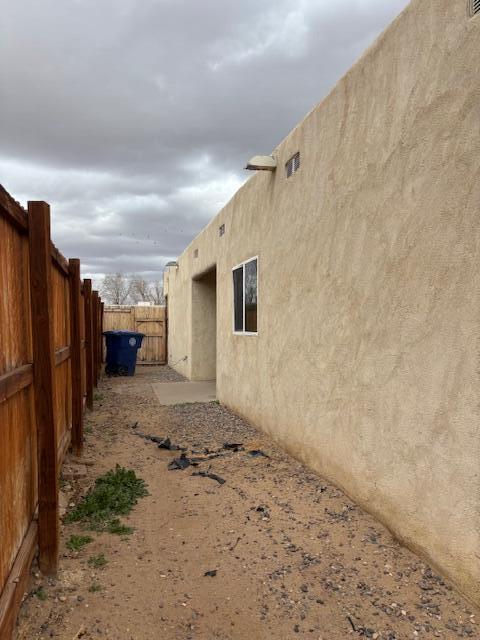 view of side of property featuring a fenced backyard and stucco siding