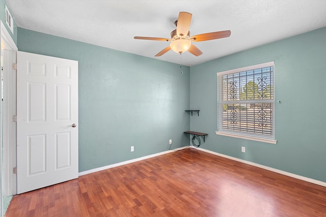 empty room with visible vents, ceiling fan, baseboards, and wood finished floors