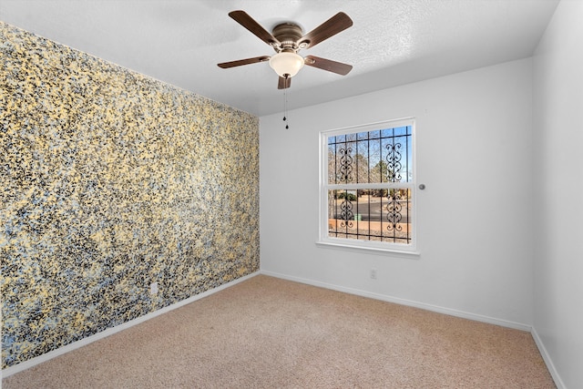 carpeted empty room featuring a textured ceiling, a ceiling fan, and baseboards