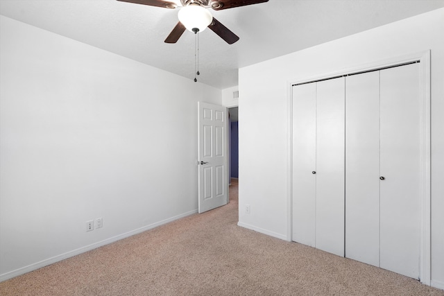 unfurnished bedroom with light carpet, ceiling fan, baseboards, and a closet