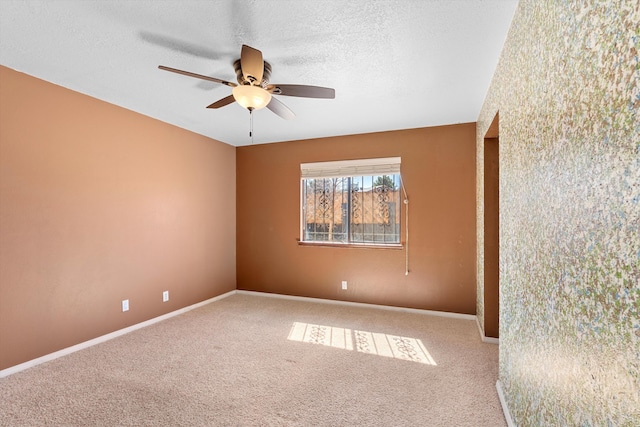 unfurnished room with a textured ceiling, carpet floors, ceiling fan, and baseboards