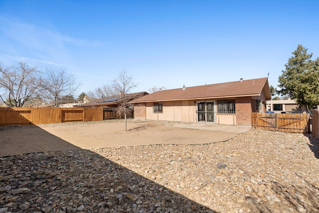 back of property featuring a fenced backyard, a patio, and brick siding