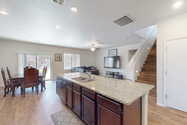 kitchen featuring light wood-style flooring, a sink, visible vents, open floor plan, and dishwasher