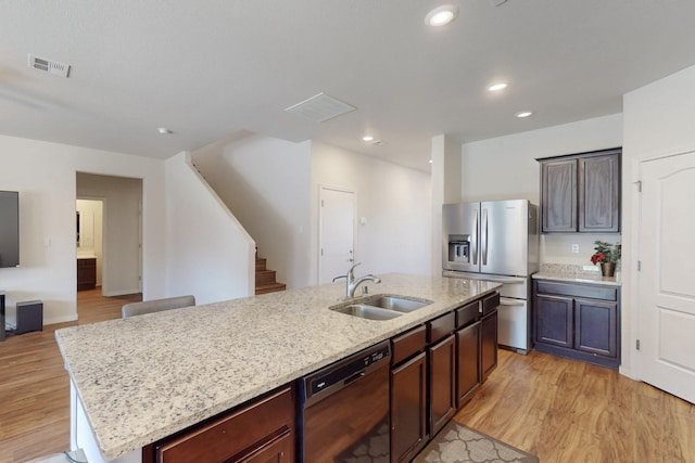 kitchen with light wood-style flooring, a sink, visible vents, black dishwasher, and stainless steel fridge