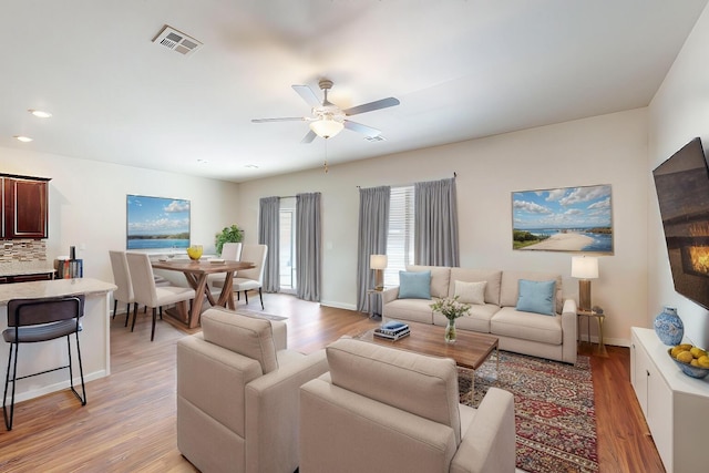 living room featuring recessed lighting, a ceiling fan, visible vents, baseboards, and light wood-type flooring