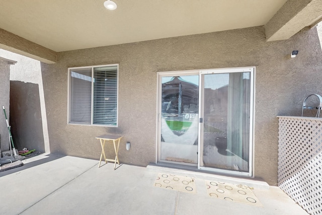 property entrance featuring a patio and stucco siding