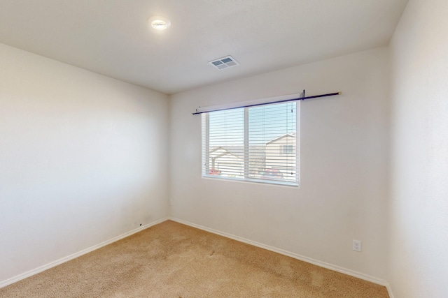 spare room featuring light carpet and baseboards