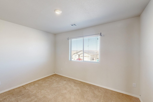 spare room featuring light carpet, visible vents, and baseboards