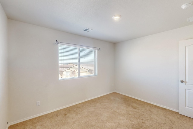 unfurnished room featuring baseboards, visible vents, and light colored carpet