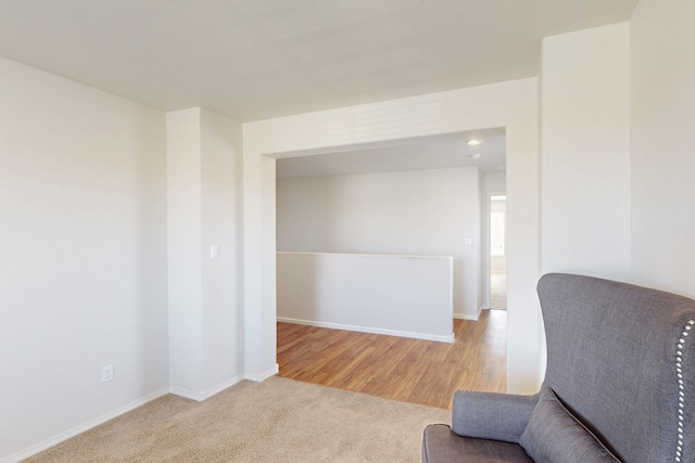 living area with carpet floors, baseboards, and wood finished floors