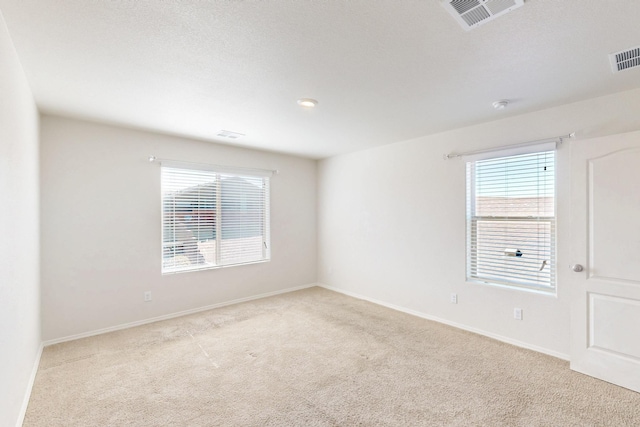 carpeted spare room with visible vents and baseboards