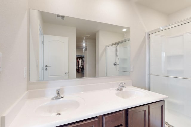 full bathroom featuring double vanity, a stall shower, a sink, and visible vents