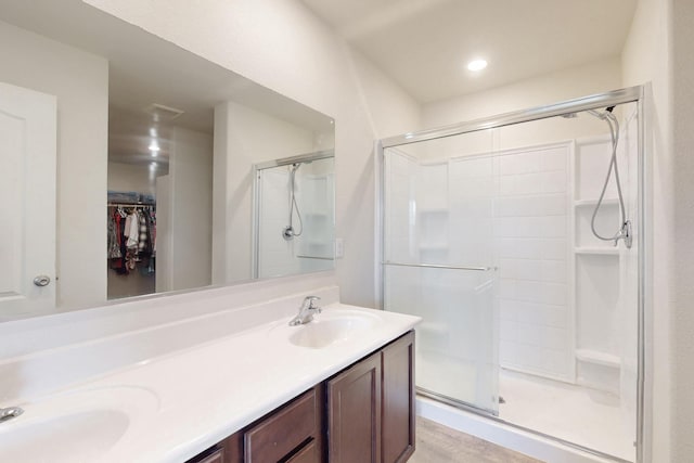 full bathroom featuring a stall shower, a walk in closet, a sink, and double vanity